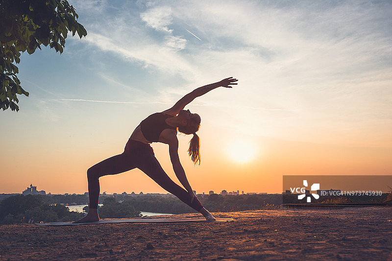 女人在户外练习瑜伽，夏日日落图片素材