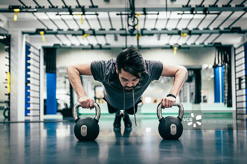日本男人在哑铃上做俯卧撑图片素材