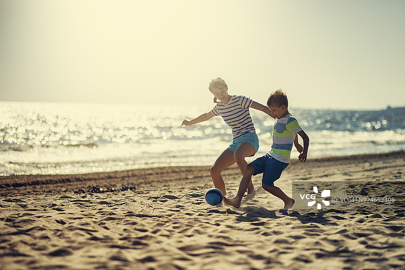 孩子们在沙滩上踢足球图片素材