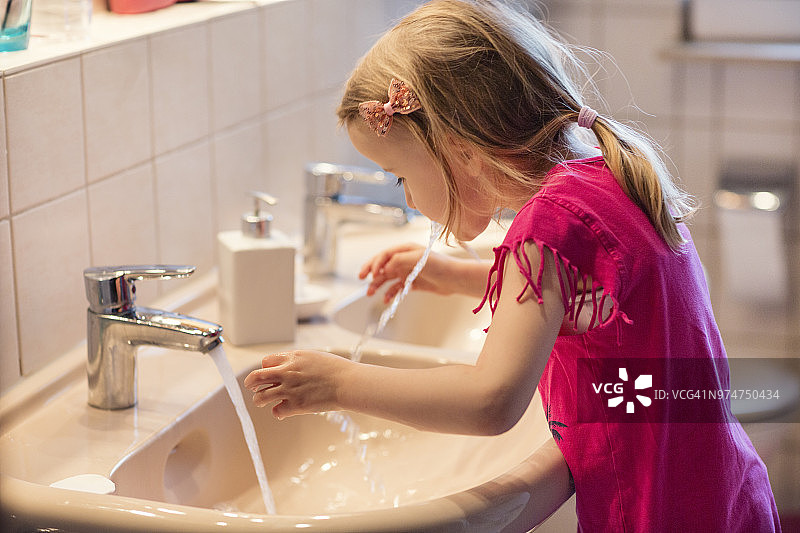 刷牙后向浴室水槽吐水的儿童图片素材