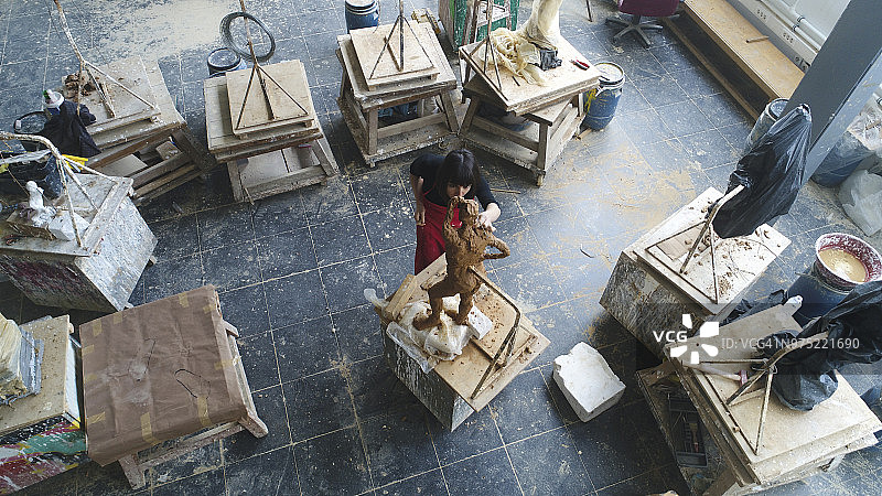 年轻女雕塑家在工作室工作图片素材