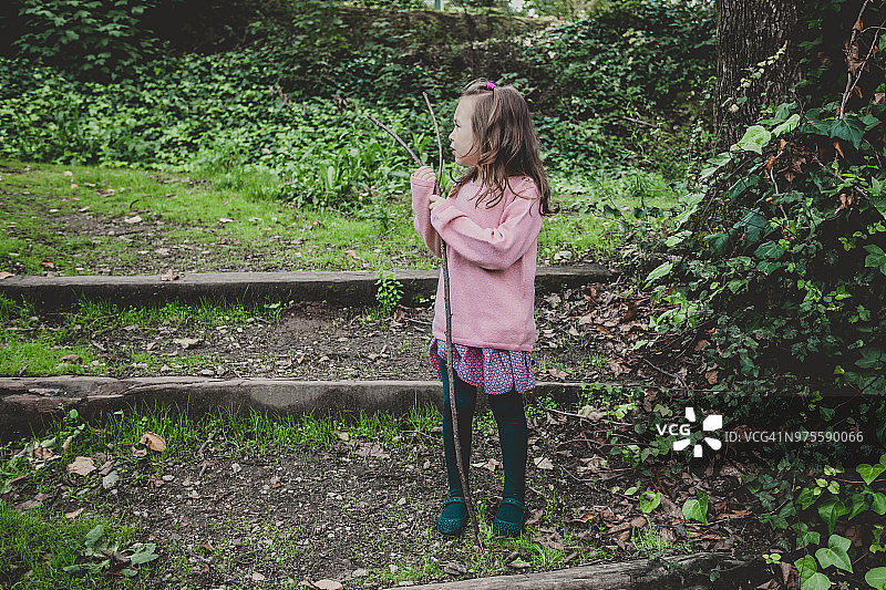 手持树枝的自然环境中的小女孩肖像图片素材