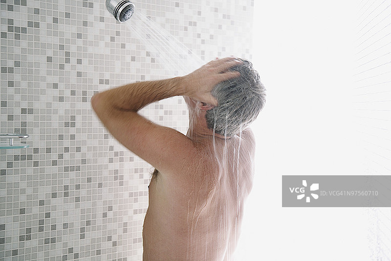 在明亮淋浴间淋浴的灰发男人图片素材