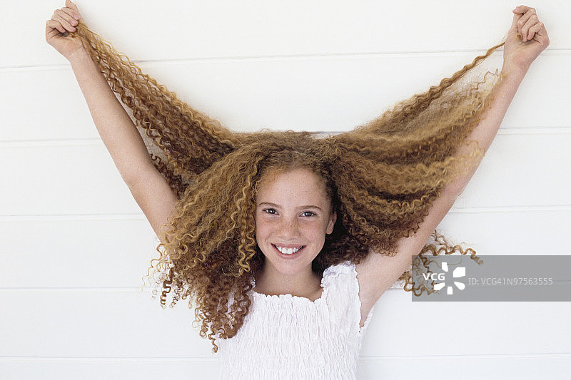 女孩举起她长长的卷发图片素材