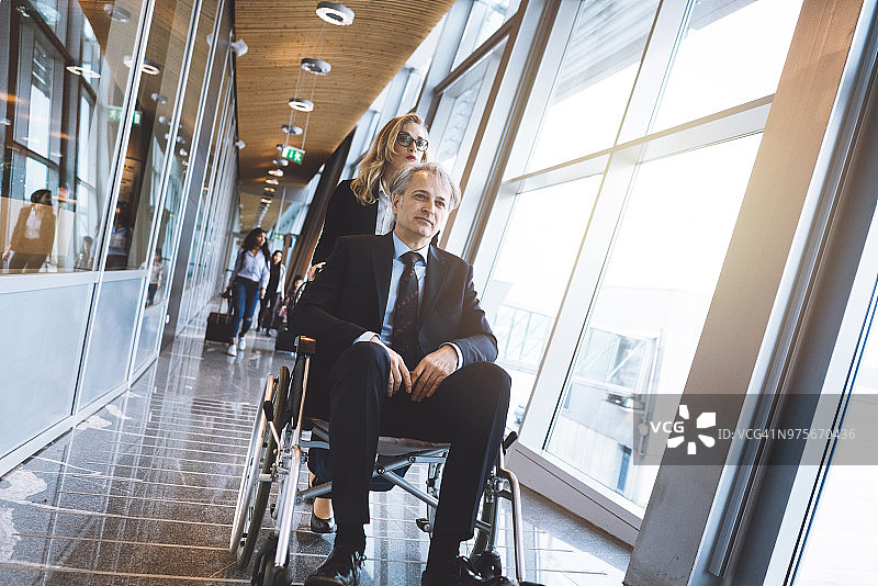 在机场帮助坐轮椅的男人图片素材