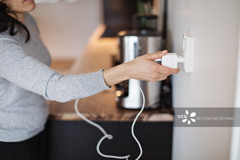 在家中将手机充电器插在墙上的女子图片素材