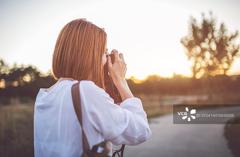 年轻女人用复古相机拍摄日落图片素材