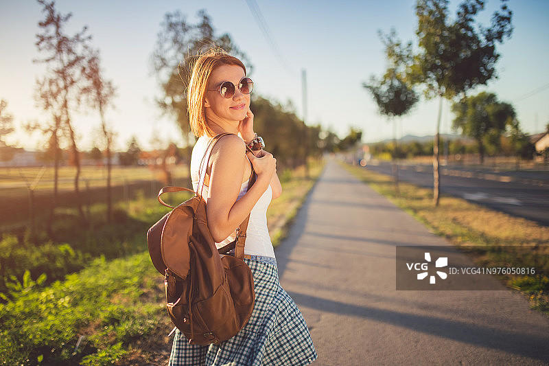 女子背着背包在阳光明媚的日子里散步和放松图片素材