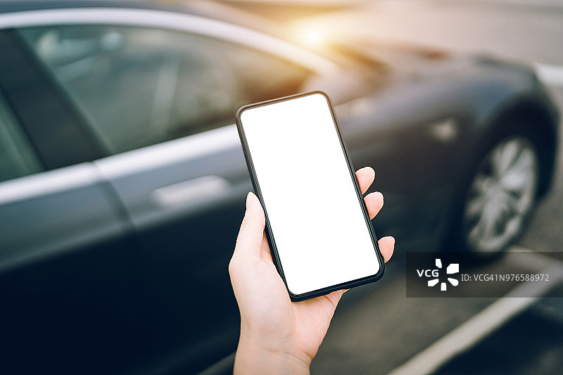 人手在城市里用智能手机对着黑色汽车的特写图片素材