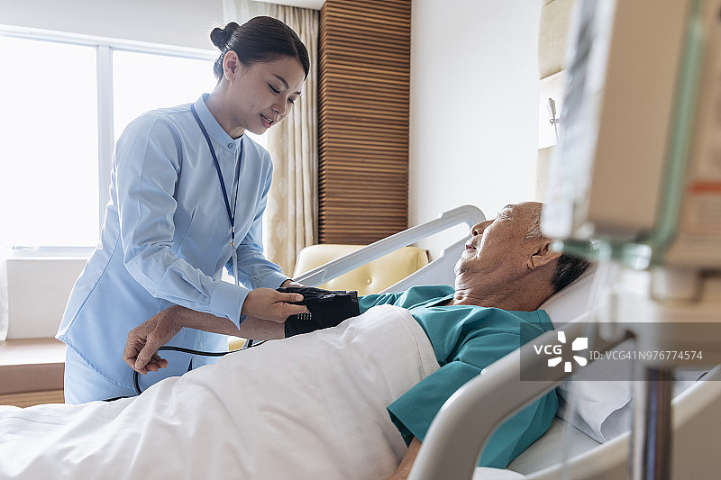 正在给老年男子调整血压计的女护士图片素材
