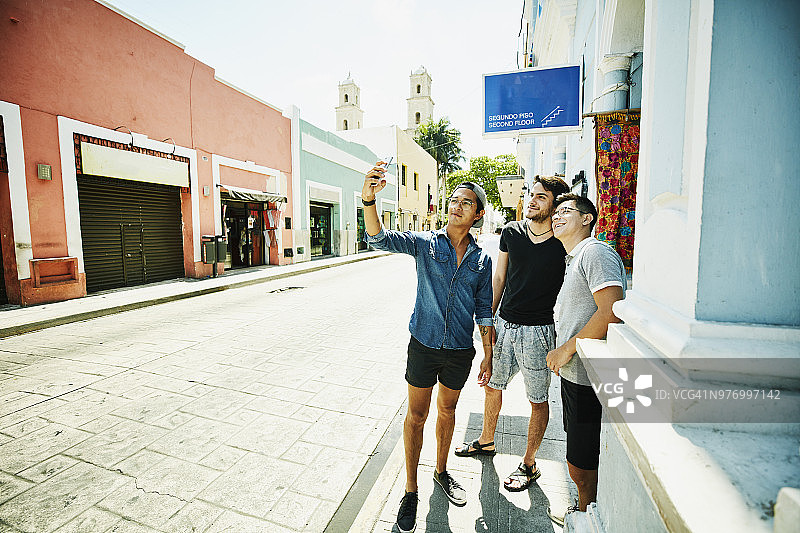 三个朋友度假购物时用智能手机自拍图片素材