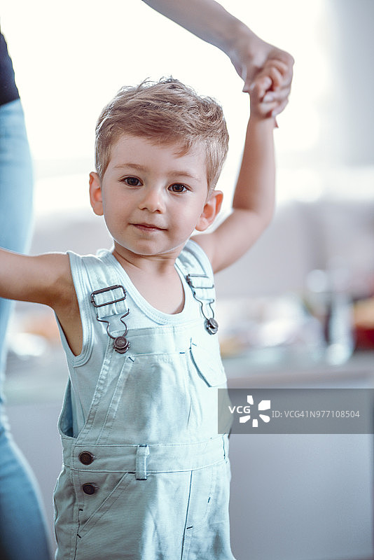在母亲的帮助下，可爱微笑的男婴尝试迈出第一步图片素材