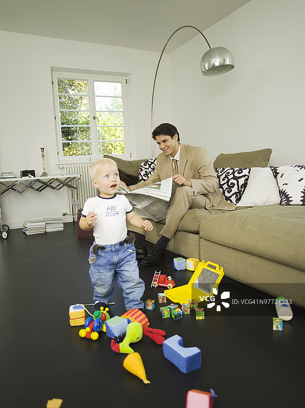 在客厅里的商人和他的幼儿儿子（12-24个月）图片素材