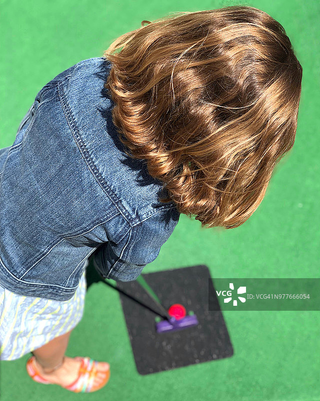 女孩在迷你高尔夫球场上推杆图片素材