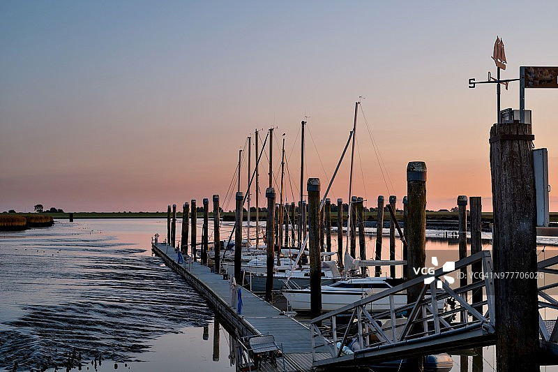 德国东弗里西亚埃姆斯河日落时分的码头停泊的船只图片素材