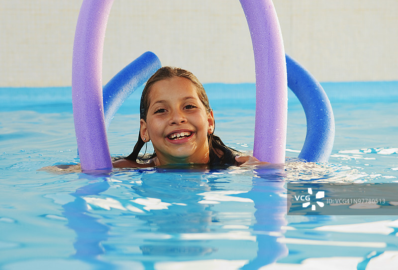 女孩在泳池里玩泳池泡沫棒图片素材