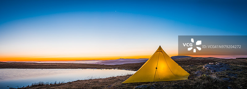日出湖边山野中的黄色帐篷露营全景图片素材