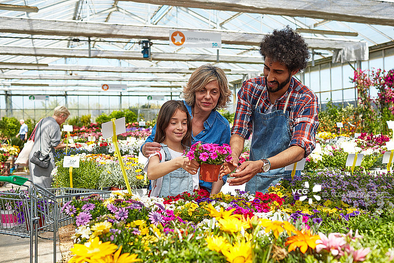 女孩在母亲和花卉中心工作人员的陪伴下购买植物图片素材