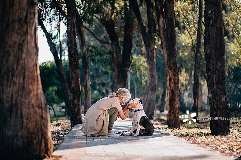 清晨乡间，年长的女人遛狗图片素材