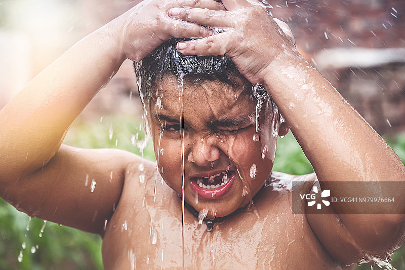 一个年轻的印度男孩在水龙头下洗澡图片素材