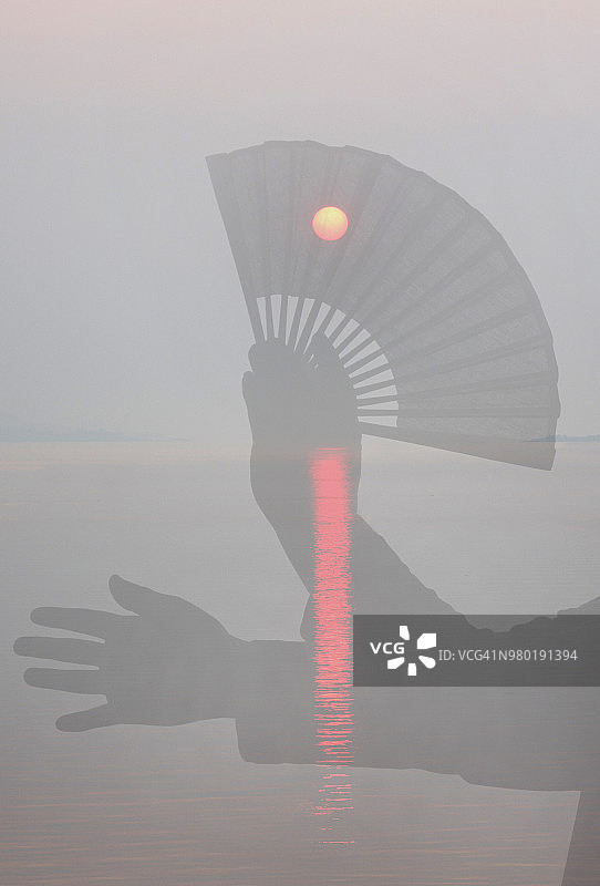 日出时手持中国风扇的剪影图片素材