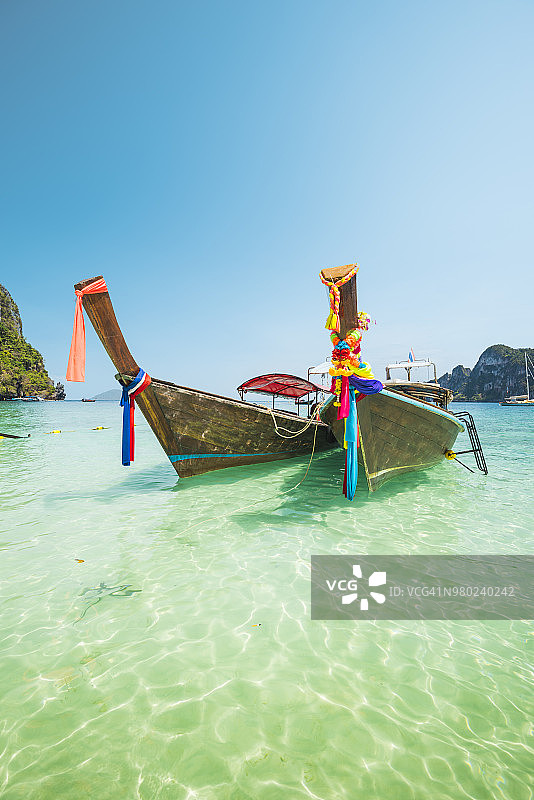 停泊在翠绿色海岸边的长尾船图片素材