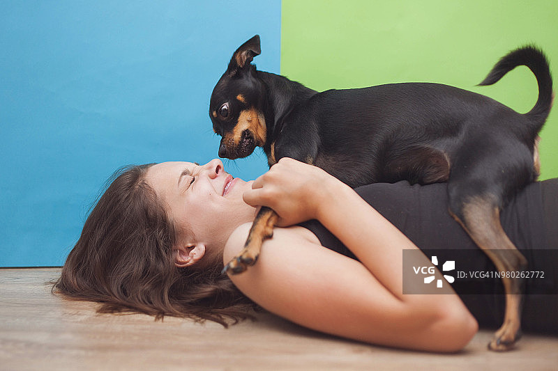 特写：12-13岁的女孩躺着和小狗玩耍图片素材