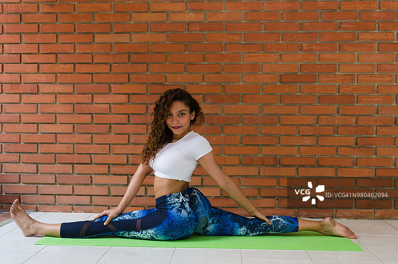 年轻女子在户外练习哈他瑜伽，展示哈奴曼式图片素材