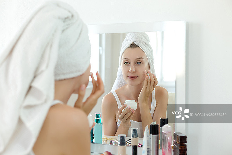 年轻女子往脸上涂抹保湿霜图片素材