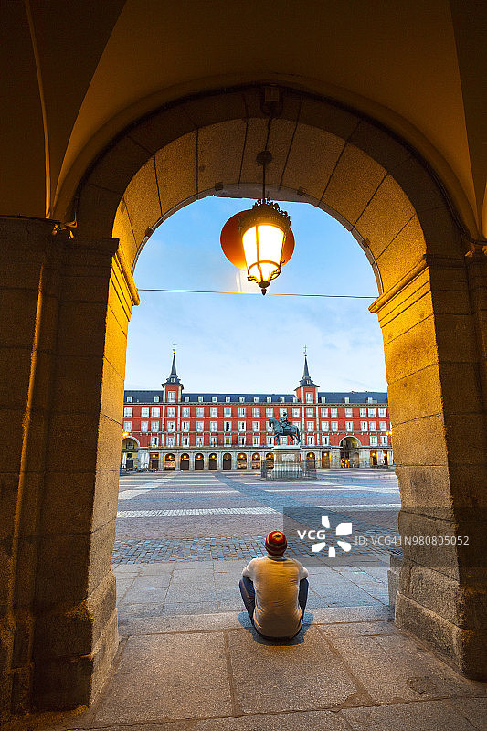 男人从西班牙马德里马约尔广场的拱廊眺望历史建筑图片素材