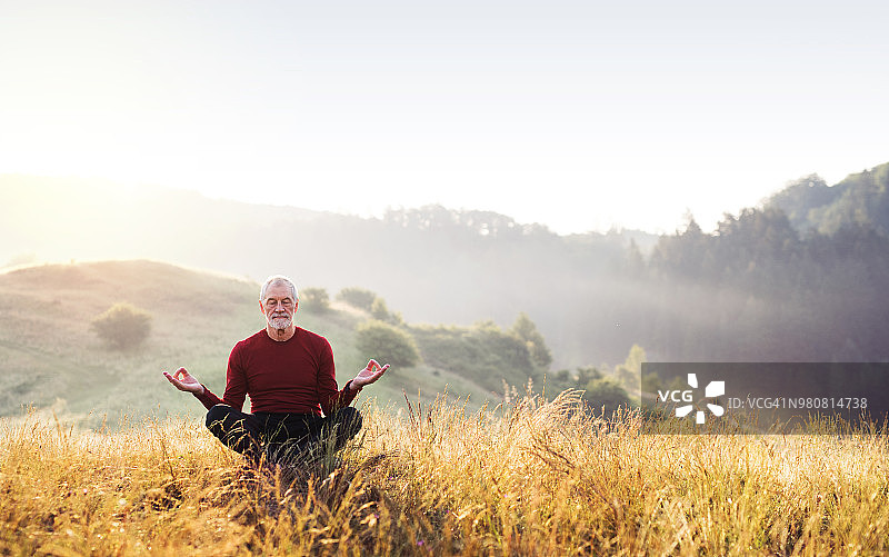 年长的男人在雾蒙蒙的早晨在户外冥想图片素材