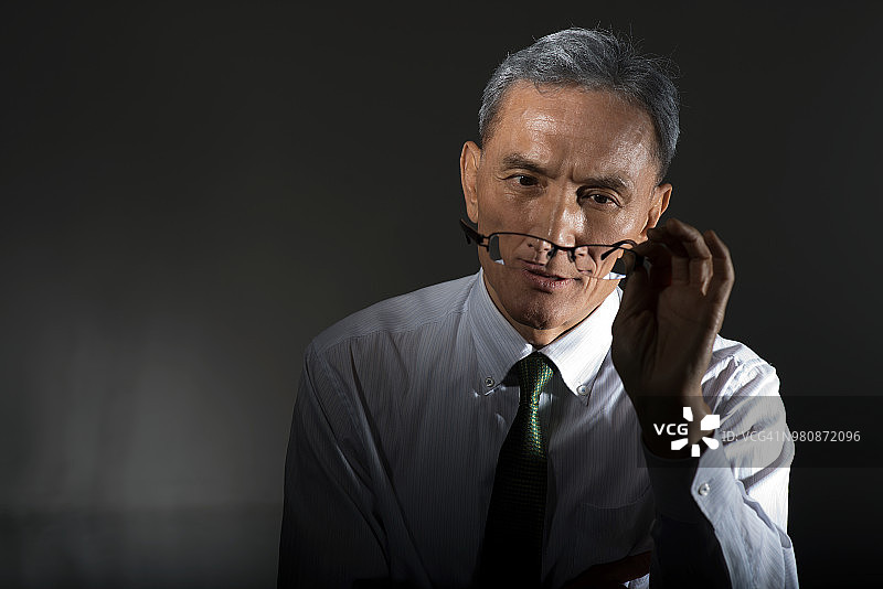中年商人拿着眼镜图片素材