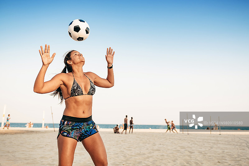 里约热内卢海滩上头顶 juggling ball 的巴西女人图片素材
