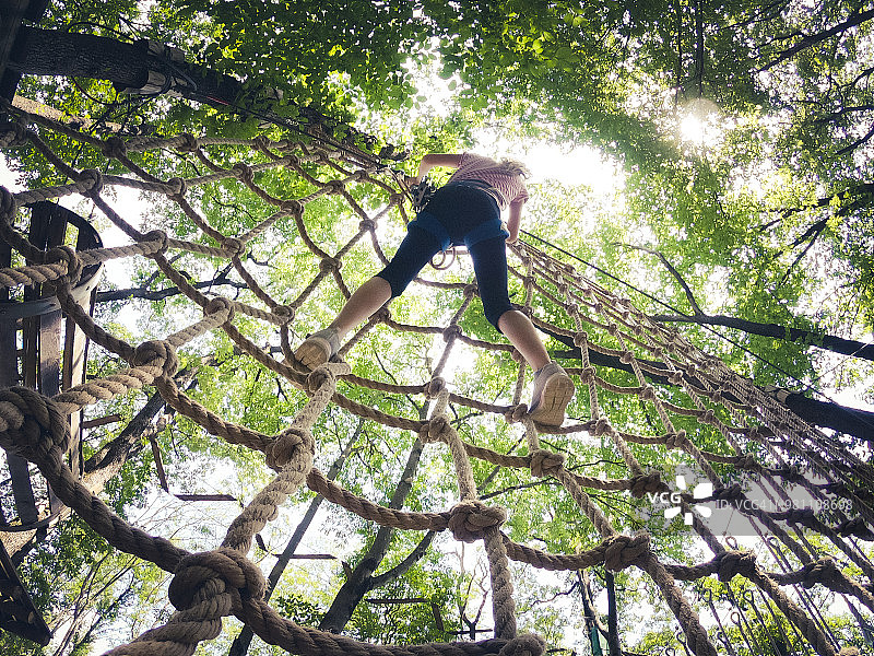 年轻女孩在游乐园攀爬绳网图片素材