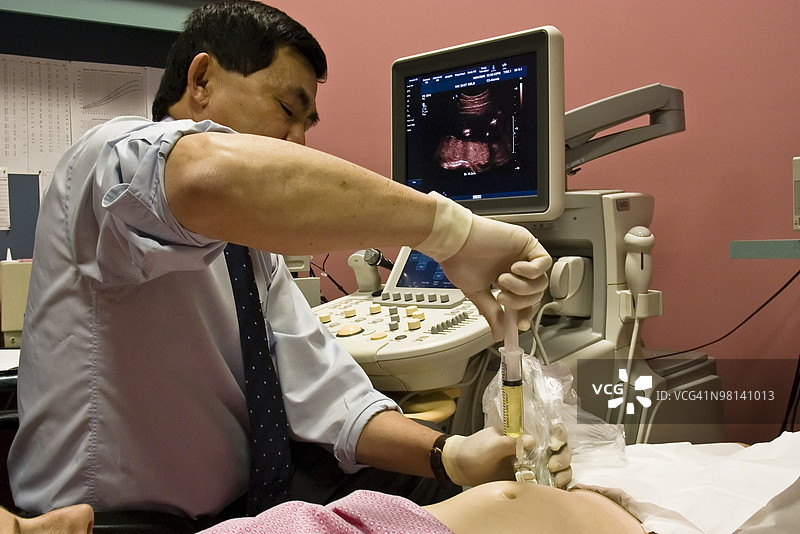 一名医生从孕妇体内抽取羊水到注射器中图片素材