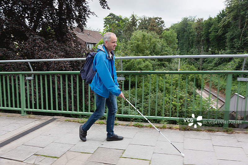 盲人拄着拐杖在街上行走图片素材
