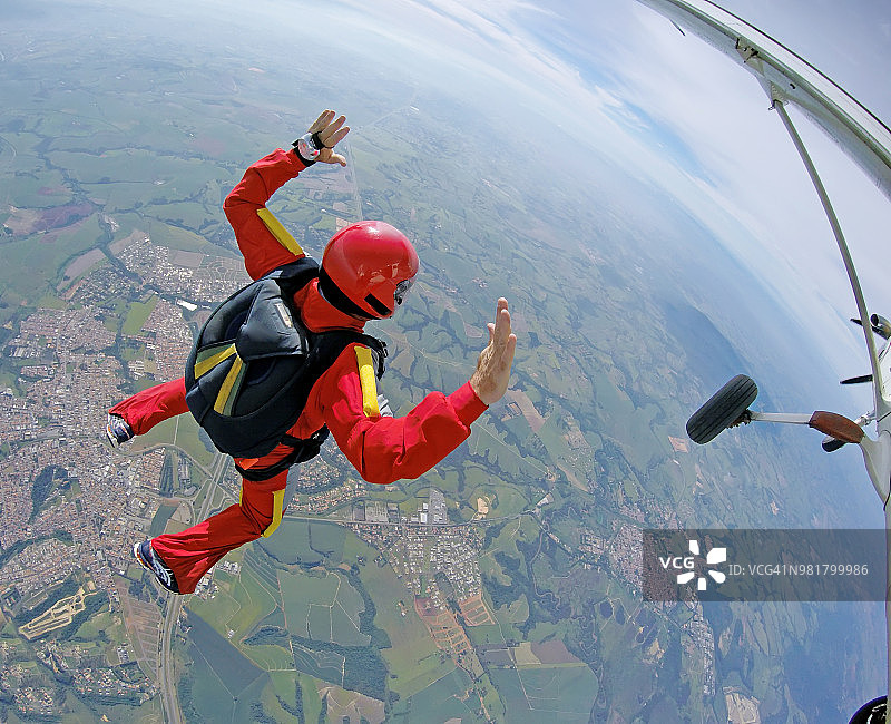 勇敢的跳伞运动员身穿红色套装跳出飞机图片素材
