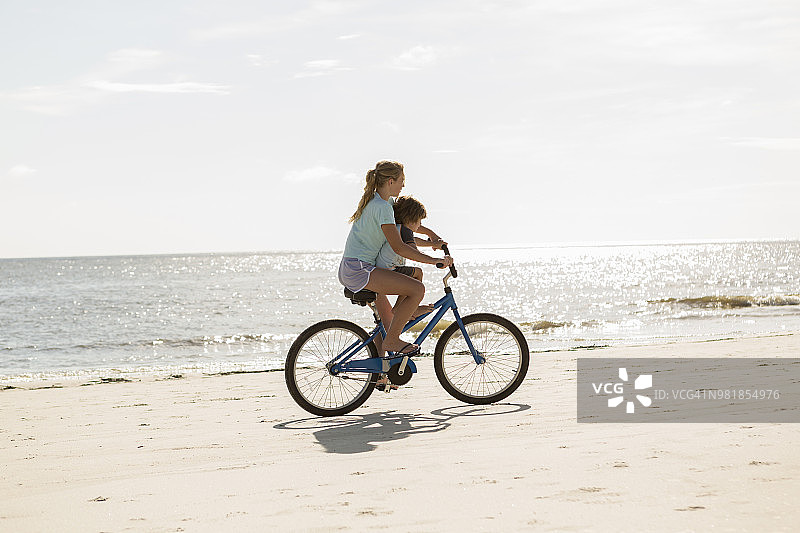 兄妹或姐弟在海滩骑自行车图片素材