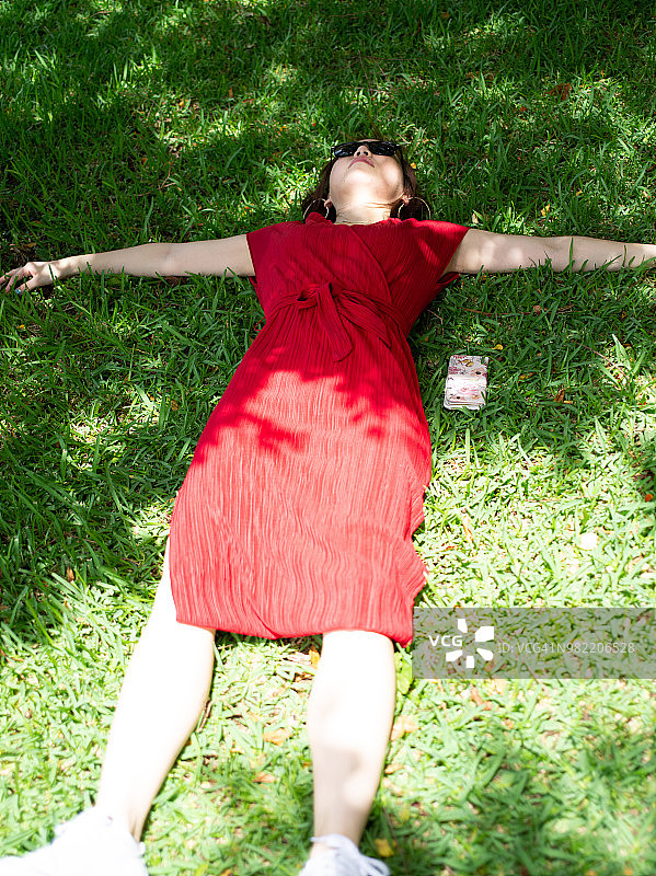 在田野上放松的红裙女人图片素材