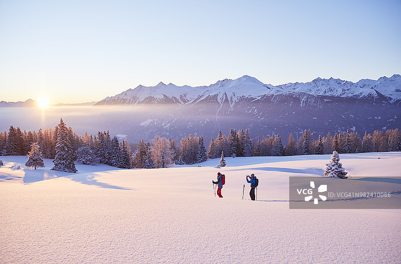 奥地利蒂罗尔州日出时分，情侣穿着雪鞋图片素材