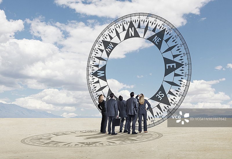 一群商务人士抬头看着高耸的指南针图片素材