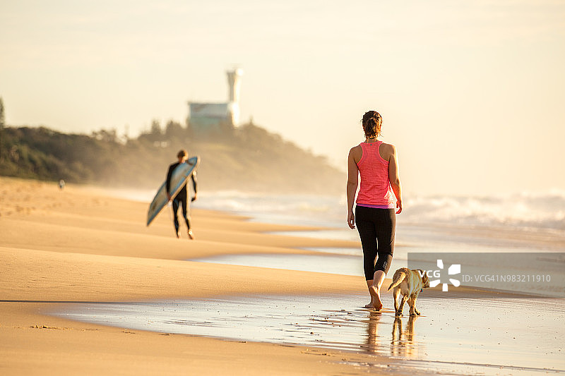 女人和拉布拉多犬在海滩上散步图片素材