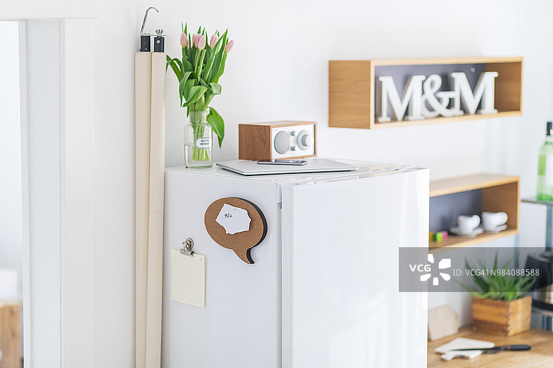 厨房冰箱上的收音机、世界地图、郁金香花瓶、笔记本电脑和智能手机及购物清单图片素材