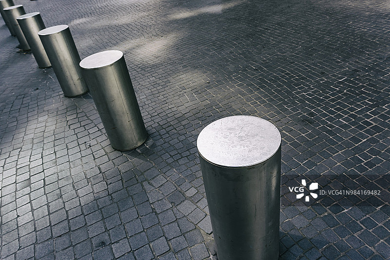 灰色瓷砖路面上不锈钢系缆桩特写图片素材
