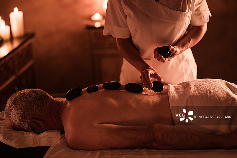 男人在水疗中心接受热石疗法图片素材