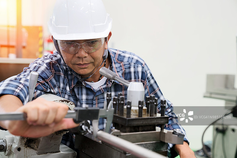 工厂里测量生产机器零件的男性工程师照片图片素材