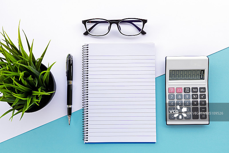 笔记本、计算器、笔、眼镜和绿色植物的俯视图图片素材