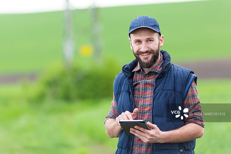 微笑的年轻男人在乡村道路上使用平板电脑图片素材
