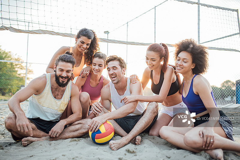 在沙滩上拿着排球微笑的运动员们图片素材