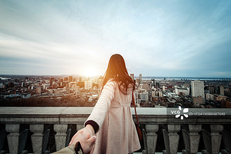 快乐的旅行情侣手牵手欣赏蒙特利尔壮观的城市天际线图片素材